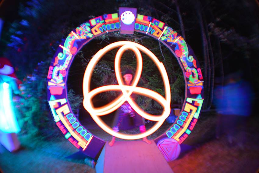 LED poi spinner at night in front of glowing art piece